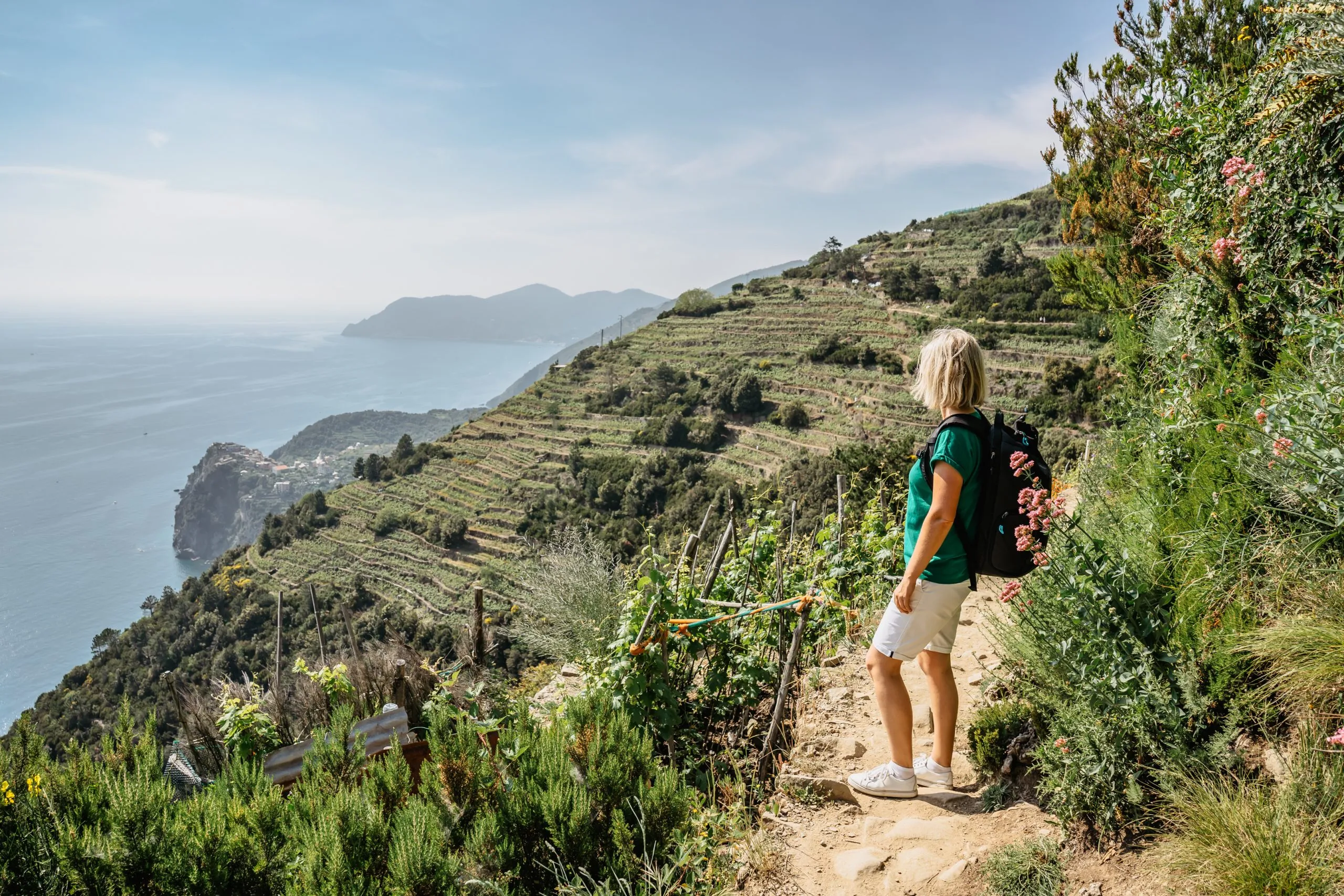 Aktive sportliche Mädchen Wandern in Cinque Terre, Italien.Blick auf Küste und Meer.Frau Backpacker auf steilen Klippe genießen Freiheit, Abenteuer, Sommerurlaub.Scenic italienischen Riviera Landschaft.Travel Hintergrund.